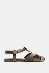 Sandalia plana estilo cangrejera con acabado efecto terciopelo en color marrón. Presenta diseño de tiras cruzadas, cierre mediante hebilla metálica lateral y punta redonda.