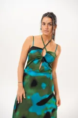 Vestido largo con estampado abstracto en tonos verdes, azules y negros. Presenta tirantes finos y cuello halter cruzado con detalle de abertura en el pecho.