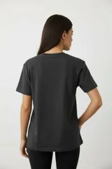 Remera de algodón manga corta con cuello redondo y corte al cuerpo. Presenta un estampado central con diseño artístico y detalles de studs aplicados.