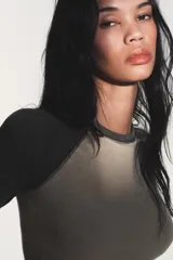 Camiseta de manga larga tipo ranglán con cuello redondo. Presenta un diseño bicolor con cuerpo en tono beige y mangas en gris jaspeado, con bajo redondeado.