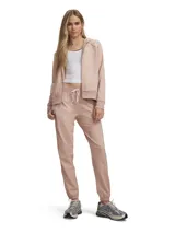 Conjunto deportivo Under Armour modelo Rival Tricot de color salmón, compuesto por una campera con capucha, cierre frontal y bolsillos, y un pantalón tipo jogger con cintura elástica ajustable y puños elásticos.