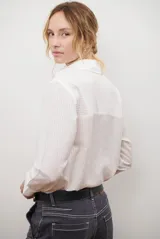 Camisa de mujer a rayas verticales blancas y rosadas, con cuello clásico, cierre de botones frontal y mangas largas con puños abotonados.