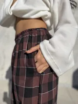 Pantalón de viyela con estampado a cuadros en tonos bordó y negro. Presenta un diseño de silueta amplia con cintura elástica y puños ajustados en los tobillos.