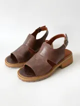 Sandalias de cuero color chocolate con suela track y taco bajo cuadrado. Poseen capellada cerrada con aberturas laterales y tira ajustable en el talón con hebilla metálica.