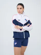 Campera deportiva Umbro del Club Nacional de Football, modelo Sky para mujer. Diseño en tonos azul marino y celeste con detalles en blanco y líneas finas rosadas, cuello alto, cierre frontal y bolsillos.