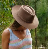Sombrero de ala ancha confeccionado en paño de lana afieltrada a mano, con copa estructurada y detalle de cinta del mismo material.