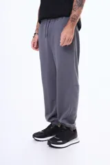 Pantalón deportivo de felpa color negro, con cintura elástica ajustable mediante cordón, puños elásticos en los tobillos y bolsillos laterales.