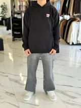 Canguro negro de corte oversize con capucha, manga larga y bolsillo tipo canguro al frente. En la espalda presenta un gran estampado gráfico con las palabras "Top Style" en blanco y rojo, acompañado de inscripciones y detalles minimalistas.