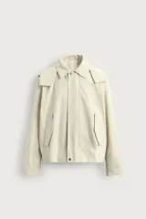Parka cropped fit de tejido técnico ligero color beige, sin forro interior, con cuello solapa, capucha desmontable y manga larga. Cuenta con bolsillos de solapa en la cadera y cierre frontal con cremallera oculta por solapa con botones a presión.