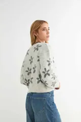 Cardigan de punto con estampado de flores, cuello redondo y cierre frontal con botones. Presenta un diseño de corte holgado con puños y ruedo acanalados.