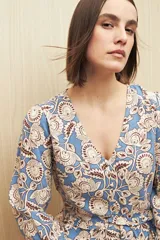 Blusa celeste con estampado floral en tonos beige y marrón, escote en V, mangas 3/4 abullonadas y frunce en la cintura.