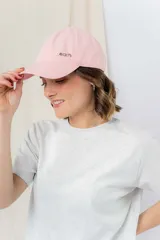 Gorra verde militar de diseño clásico con visera curva y aplique metálico plateado con la inscripción "Peach" en el lateral frontal. Cuenta con tira ajustable en la parte trasera.