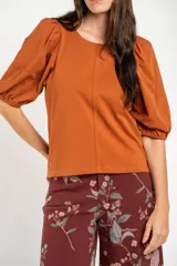 Remera de algodón negro con mangas cortas abullonadas, cuello redondo y costura central frontal.