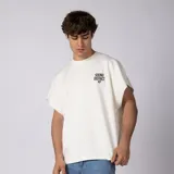 Remera oversize color blanco de interlock con sisas al corte, cuello redondo y estampa pequeña frontal con texto en negro.