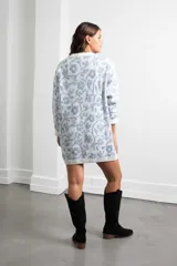 Vestido tejido de punto con diseño oversize, estampado floral en tonos celeste y blanco, cuello redondo y mangas largas con puños acanalados.