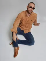 Camisa marrón de pana de manga larga con cuello abotonado y bolsillo en el pecho.