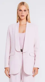 Blazer de sastrería color rosado, con diseño estructurado, solapas redondeadas y bolsillos laterales con solapa.