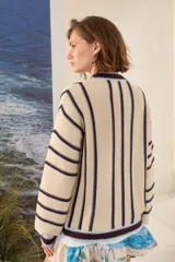 Cardigan de punto a rayas verticales en tonos marrón chocolate, blanco y amarillo, con escote en V, mangas largas y cierre frontal con botones.