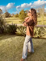 Camisa color marrón de tela símil gamuza, con cuello y puños con estampado a cuadros.