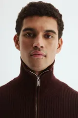 Buzo de punto acanalado en color bordó, con cuello elevado y cierre frontal parcial. Presenta un diseño de corte estándar con puños y bajo recto acanalados.