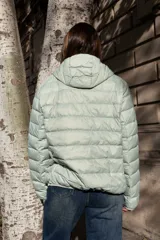 Campera puffer ultraliviana color beige, con diseño acolchado horizontal, capucha incorporada, cierre frontal y bolsillos laterales.