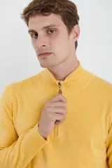 Sweater verde oliva de tejido acrílico con textura similar al cashmere, corte clásico, cuello alto con cierre metálico y tirador de cuerina ecológica.