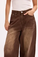 Pantalón de jean estilo baggy, de corte amplio y tiro medio, confeccionado en denim negro con textura de pana fina. Presenta diseño de cinco bolsillos, cierre frontal con botón metálico y cremallera, y perneras holgadas.