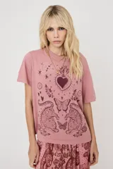 Remera rosada de manga corta con estampado frontal de estilo bohemio que incluye un corazón sagrado, mariposas, jaguares y detalles en strass.