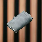 Billetera delgada de cuero sintético color gris oscuro/negro, con mecanismo de eyección para tarjetas y cierre a presión. El nombre "BALEINE" está grabado en la parte inferior frontal.