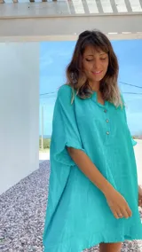 Túnica verde agua de lino rústico, corte amplio, cuello mao con abertura parcial abotonada y mangas cortas con terminación desflecada.