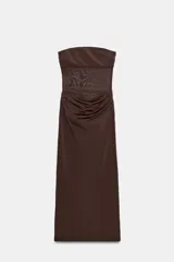 Vestido midi de escote recto sin tirantes, color marrón, con diseño semitransparente en la sección del abdomen y detalle drapeado en la falda. Cuenta con cierre lateral.