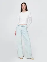 Jean de tiro alto con corte wide leg y acabado en lavado claro. Presenta diseño de cinco bolsillos, cierre frontal con botón y cremallera, y ruedo deshilachado.