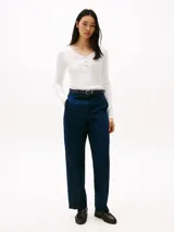 Remera blanca de algodón con textura acanalada, corte slim, cuello redondo con tapeta de botones dorados y manga larga.