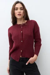 Cardigan bordó de manga larga con cuello redondo y cierre frontal de botones. Presenta un tejido con patrón de estructuras.