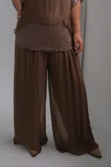 Pantalon de corte palazzo, confeccionado en tela semitransparente color chocolate, con cintura elástica y caída fluida.