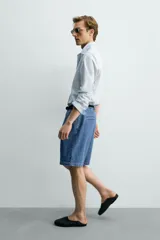 Bermuda de denim de algodón con corte relaxed fit, cintura con pliegues dobles en el delantero, bolsillos laterales y traseros de doble vivo, con efecto lavado y cierre frontal con cremallera y botón.