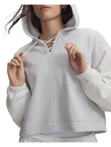 Buzo con capucha Under Armour modelo Rival Fleece Laceup, de color celeste claro con mangas texturizadas en tono gris melange. Cuenta con diseño crop, cordones cruzados decorativos en el cuello y puños y bajo acanalados.