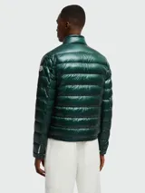 Campera corta tipo puffer de Moncler, modelo Acorus, en color verde oscuro con acabado brillante. Presenta diseño acolchado horizontal, cuello alto con cierre de broche, cierre frontal completo y bolsillos laterales con cierre.