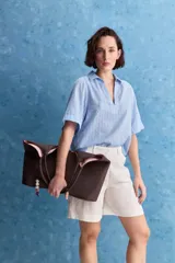 Blusa celeste de manga corta con cuello camisero y escote en V, confeccionada en tejido liviano con textura sutil y estampado de lunares.