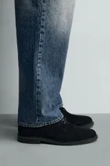 Zapato tipo derby con cordones, confeccionado en piel con acabado de serraje. Presenta horma redonda y suela a contraste.