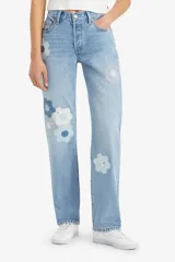 Pantalón de jean celeste con apliques florales geométricos en tonos azules y blancos.