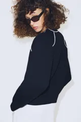Jersey de punto de manga larga con cuello redondo, diseño en color azul marino con detalles de vivo en color blanco en el cuello y las costuras de las mangas.