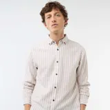 Camisa de manga larga confeccionada en mezcla de lino y algodón, con diseño de rayas verticales en tonos beige y blanco, cuello con botones y cierre frontal de botonadura central.