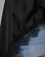 Blusa de satén color negro, con diseño asimétrico de un solo hombro y caída fluida. Presenta detalles de encaje en los bordes.