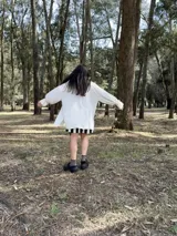 Camisa oversize de fibrana color crudo con botones negros en forma de corazón y mangas largas con puños elásticos.