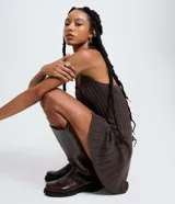 Vestido corto marrón de corte evasé, sin mangas y con escote halter. Está confeccionado en malla con efecto de punto texturizado y cuenta con un lazo para atar en el cuello.