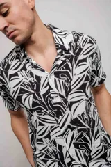 Camisa de manga corta con estampado de hojas en blanco y negro, confeccionada en rayón.