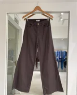 Pantalón de jean color marrón tabaco, de corte recto y pierna ancha, con tajo lateral en el ruedo.