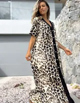 Vestido largo de corte holgado con estampado animal print de leopardo. Presenta una botonadura frontal completa sobre una franja vertical de color negro que recorre el centro de la prenda, cuello en V y mangas cortas.