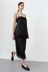 Falda midi de tiro alto confeccionada en tejido efecto piel color negro. Presenta un diseño de corte recto con bajo acabado en aplicación de encaje a tono y abertura en la espalda. Cierre mediante cremallera oculta en la costura posterior.